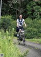 A woman riding a bike down a dirt road.