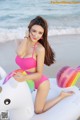 A woman in a pink bikini sitting on an inflatable unicorn.