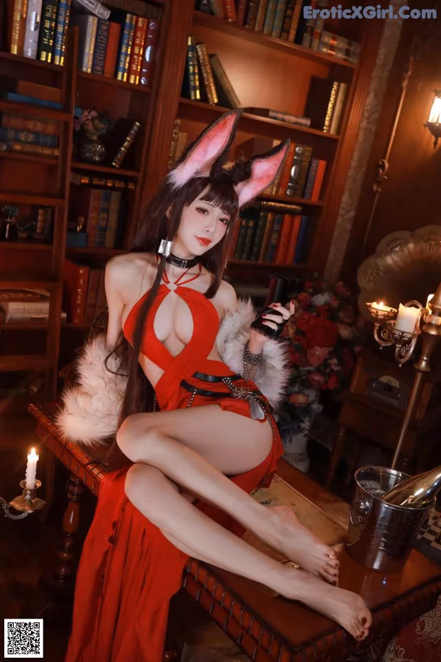 A woman in a red dress sitting on a table.