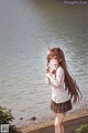 A girl in a school uniform standing by the water.