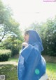 A woman in a blue hooded sweatshirt is standing in the grass.