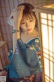 A woman in a blue kimono is posing for a picture.